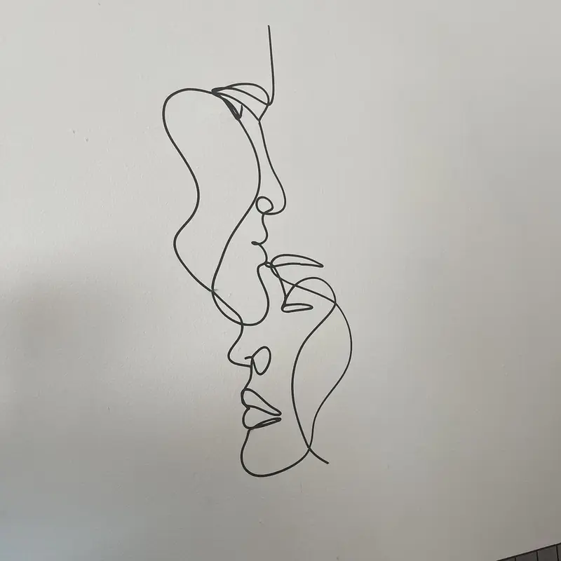 Dibujo de líneas de dos rostros en una pared blanca del centro